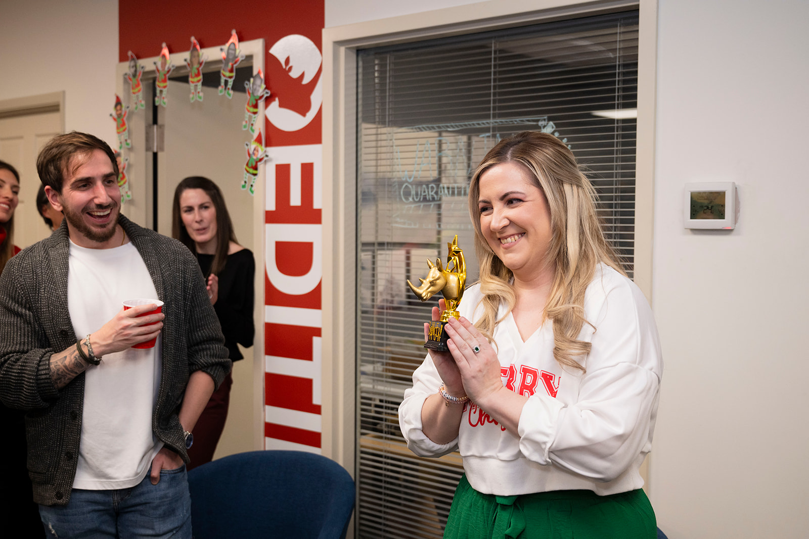 A colleague holding up a gold rhino trophy while teammates applaud around them